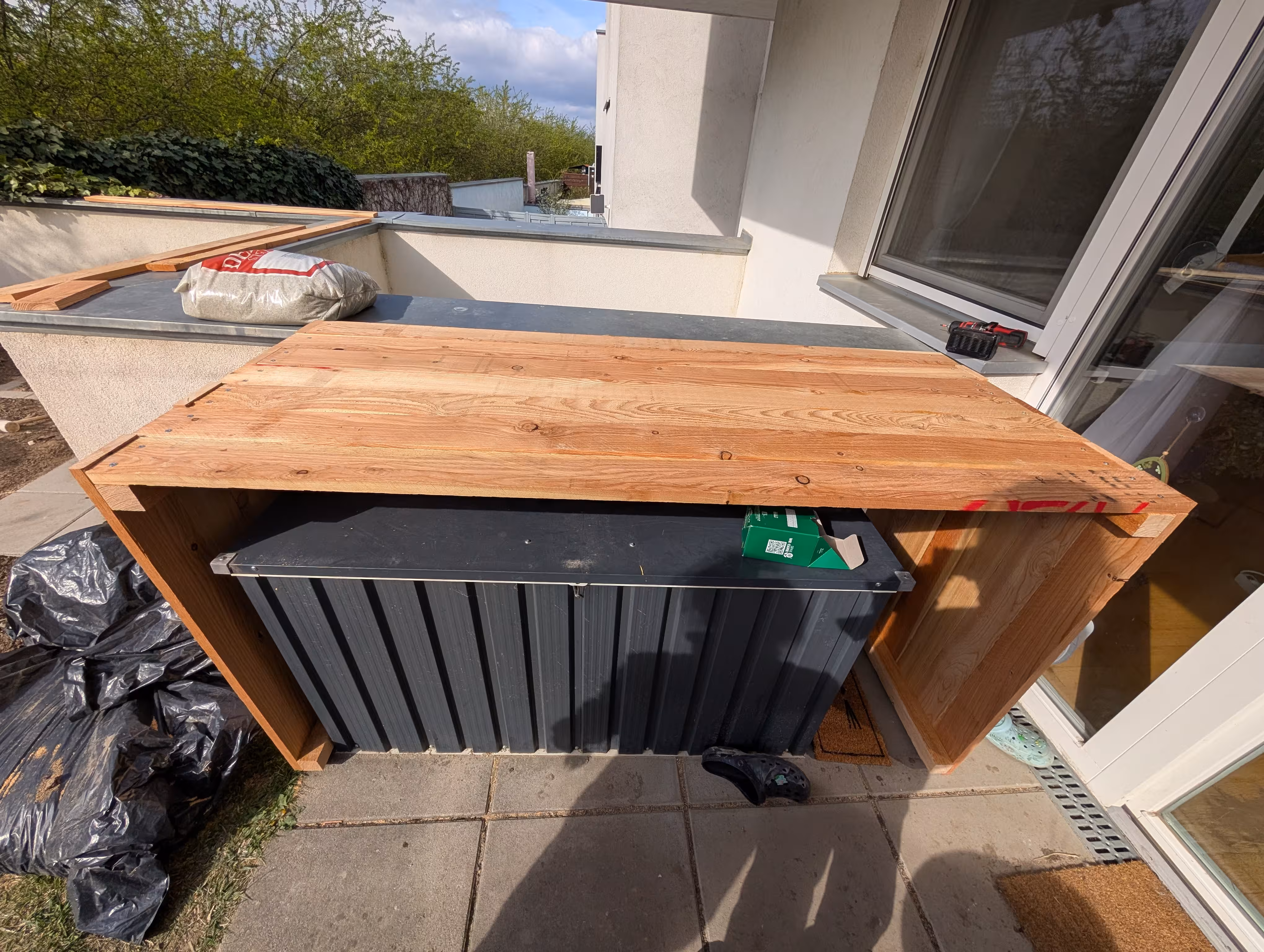 Three sides of the planter box are screwed together. The U-shaped construct rests over a garden toolbox